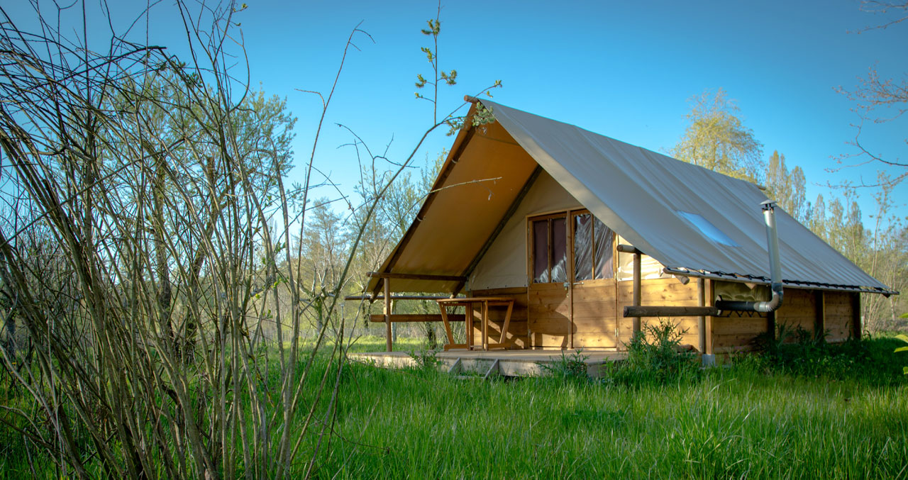 Chalet en bois et toile au milieu des pré avec des arbres