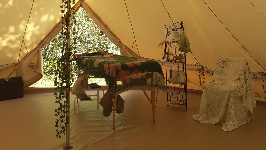 Une grande tente avec une table de massage et des petites plantes pour le bien-être